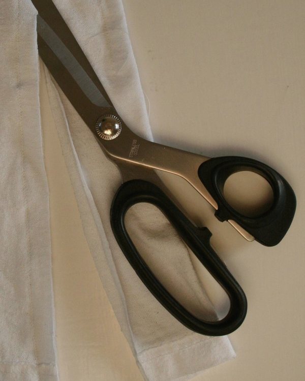 Dressmaking scissors laid on the white T-shirt fabric