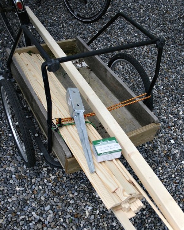 Timber and a galvanised ground spike loaded in the bicycle trailer on the gravel
